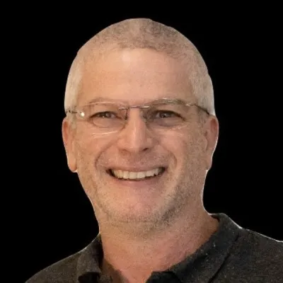 Smiling man with glasses against a black background.