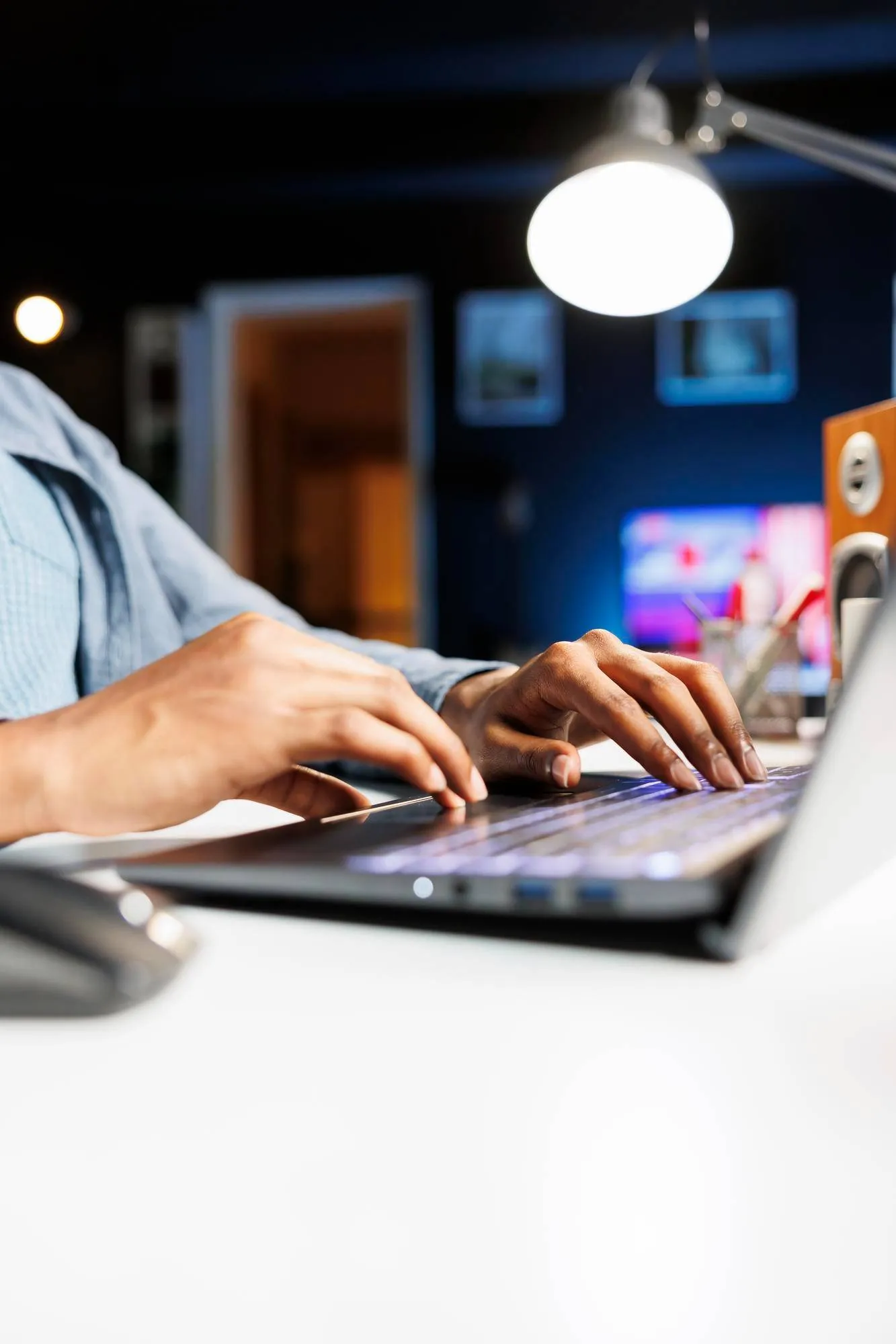 Hands typing on a laptop keyboard under a desk lamp. Law Firm Content Marketing.