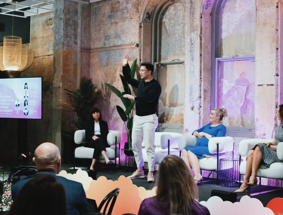 Panel discussion at a law firm SEO conference. Speaker gestures while panelists listen.